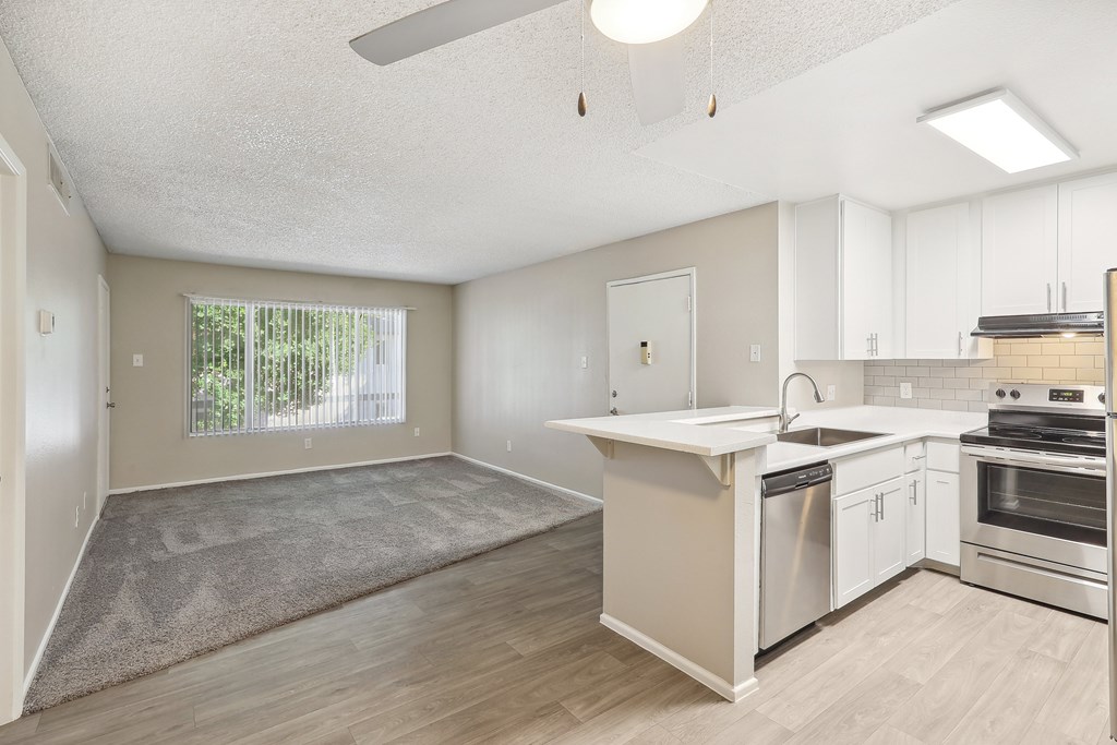 an empty kitchen and living room with white cabinets and a window